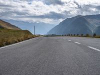 a motorcycle driving along a curvy country side road in front of a mountain range