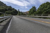 a motorcycle is driving through a rural roadway near some trees and mountains above a mountain