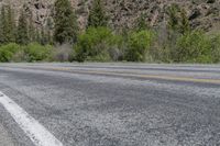 a motorcycle is sitting on the side of the road in the mountains with trees behind it