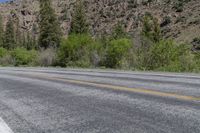 a motorcycle is sitting on the side of the road in the mountains with trees behind it