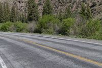 a motorcycle is sitting on the side of the road in the mountains with trees behind it