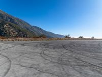 a motorcycle parked on a mountain road next to hills and a hill side road with tire tracks in the concrete