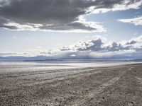 a lone motor cycle is parked on a beach at low tide waterside with mountains in the background