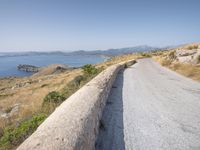 a lone motorcycle parked on a road beside the sea, with a wall separating the road