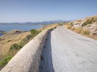 a lone motorcycle parked on a road beside the sea, with a wall separating the road