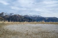 a motorcycle is parked on a dry meadow, and mountain view from behind it,