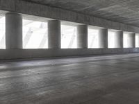 a motorcycle parked under the freeway by an overpass with columns in the background that make it look like a long corridor