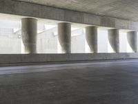 a motorcycle parked under the freeway by an overpass with columns in the background that make it look like a long corridor