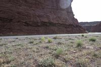 a person riding a motorcycle along a narrow road through rocks and sand cliffs a grassy area on both sides