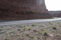 a person riding a motorcycle along a narrow road through rocks and sand cliffs a grassy area on both sides