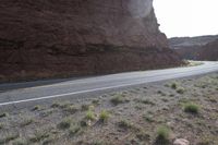 a person riding a motorcycle along a narrow road through rocks and sand cliffs a grassy area on both sides