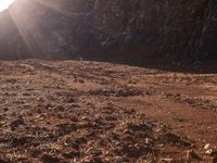 a motorcycle is parked in front of some mountains and rocks while the sun shines on it