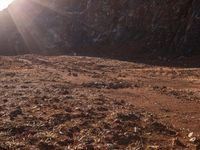 a motorcycle is parked in front of some mountains and rocks while the sun shines on it