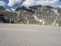 a motorcycle parked on a gravel road in front of a mountain range in the alps