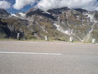 a motorcycle parked on a gravel road in front of a mountain range in the alps