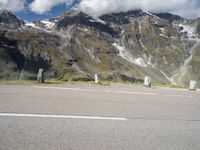 a motorcycle parked on a gravel road in front of a mountain range in the alps