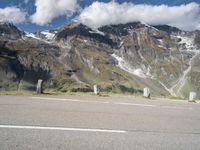 a motorcycle parked on a gravel road in front of a mountain range in the alps