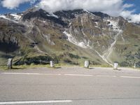 a motorcycle parked on a gravel road in front of a mountain range in the alps