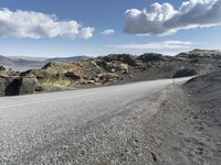 the motorcycle is parked on the rocky road outside of the mountains with rocks and moss