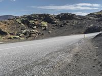 the motorcycle is parked on the rocky road outside of the mountains with rocks and moss