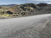 the motorcycle is parked on the rocky road outside of the mountains with rocks and moss