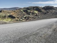 the motorcycle is parked on the rocky road outside of the mountains with rocks and moss