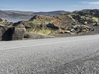 the motorcycle is parked on the rocky road outside of the mountains with rocks and moss