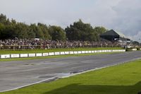 spectators watch on as a motorcycle racing goes down the track at a race event in a large open air arena