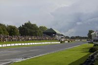 spectators watch on as a motorcycle racing goes down the track at a race event in a large open air arena