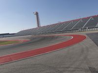 a person rides on a motorcycle on the track in front of an empty stadium, near the water