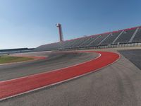 a person rides on a motorcycle on the track in front of an empty stadium, near the water