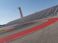 a person rides on a motorcycle on the track in front of an empty stadium, near the water