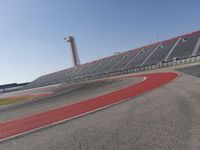 a person rides on a motorcycle on the track in front of an empty stadium, near the water