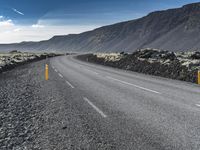 a person riding a motorcycle down the middle of the road on an asphalt mountain side