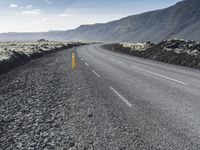 a person riding a motorcycle down the middle of the road on an asphalt mountain side