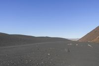 people riding on a motorcycle in the desert and mountains are in background while there is no one in the field or the sky