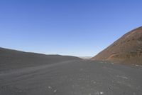 people riding on a motorcycle in the desert and mountains are in background while there is no one in the field or the sky