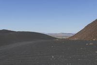 people riding on a motorcycle in the desert and mountains are in background while there is no one in the field or the sky