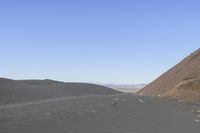 people riding on a motorcycle in the desert and mountains are in background while there is no one in the field or the sky