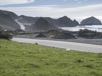 a person on an ocean motorcycle rides along a road near the water with cliffs in the background