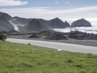 a person on an ocean motorcycle rides along a road near the water with cliffs in the background