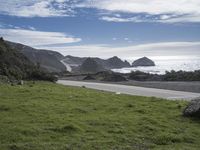 a person on an ocean motorcycle rides along a road near the water with cliffs in the background