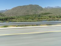 a man on a motorcycle rides down the highway toward some mountains in a blurry photograph