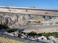 a man riding a motorcycle down the side of a mountain road in a canyon near the sea