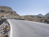 a person riding a motorcycle on a road near some mountains or mountains with some rock