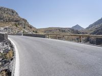 a person riding a motorcycle on a road near some mountains or mountains with some rock