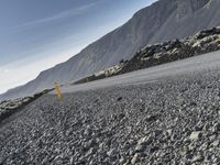 a person riding a motorcycle down a large rocky slope near the mountains, near a mountain top