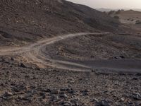 a truck on a dirt road in the desert with rocks and stones on the ground