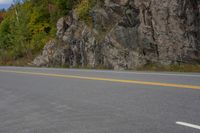 a man riding a motorcycle down the side of a road next to an empty road