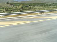 a man riding his motorcycle down the highway with hills in the distance near him in a city